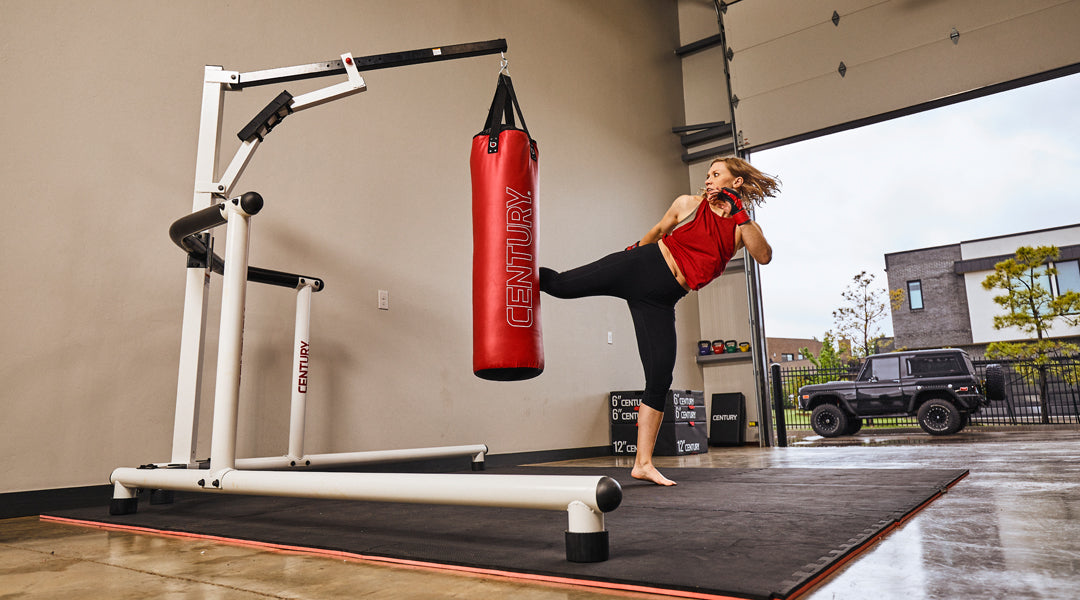 girl kicking hanging bag on bag stand